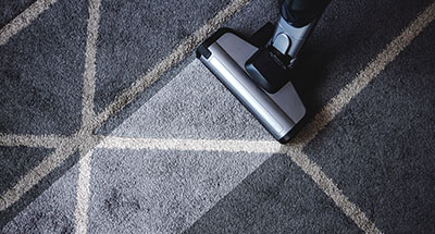 a carpet cleaner rolling over a rug and leaving a clean, lighter strip in the middle
