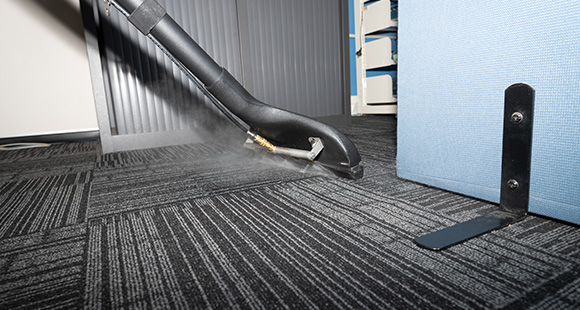 a person using a steam carpet cleaner to clean the carpet of an office